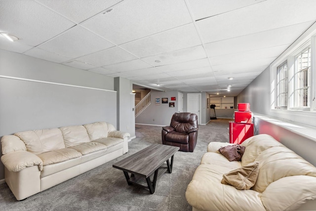 carpeted living area with a drop ceiling and stairway