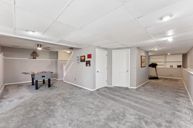 finished basement with baseboards, carpet, stairway, and a paneled ceiling