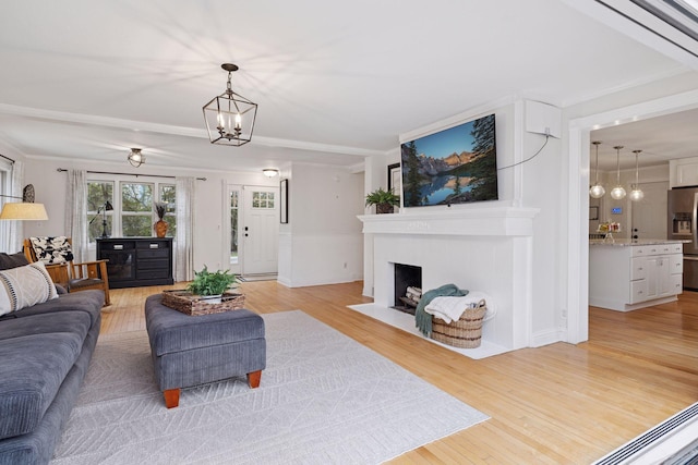 living room with a fireplace with flush hearth, light wood-style flooring, and a chandelier
