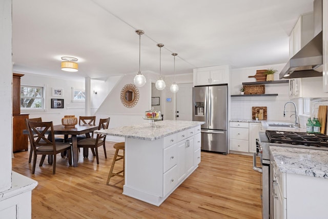 kitchen with open shelves, a sink, light wood finished floors, appliances with stainless steel finishes, and backsplash