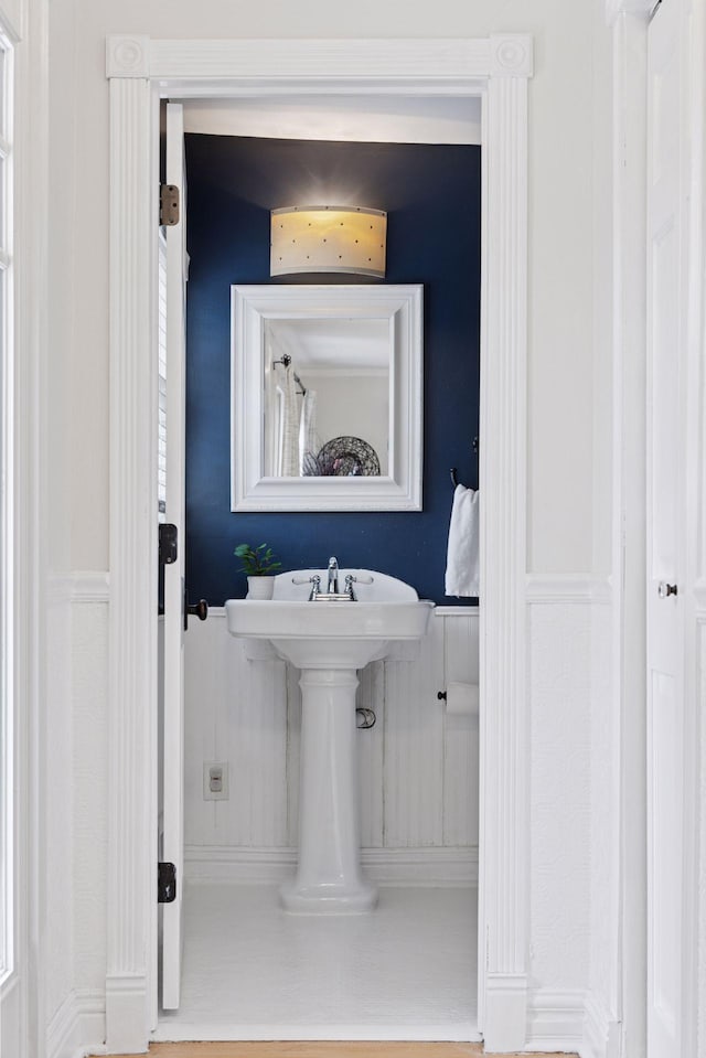 bathroom with wainscoting and a decorative wall