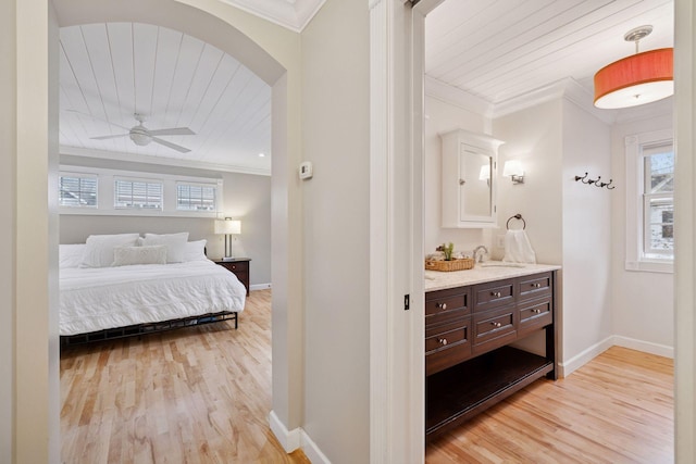 bedroom with light wood-style floors, ornamental molding, baseboards, and a sink