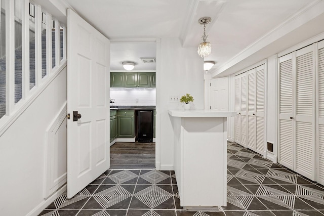 interior space with fridge, light countertops, green cabinetry, dark tile patterned flooring, and decorative light fixtures