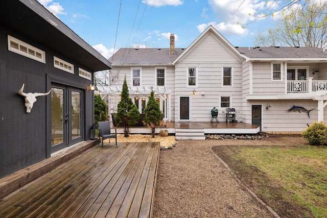 back of property featuring a chimney, roof with shingles, french doors, and a deck