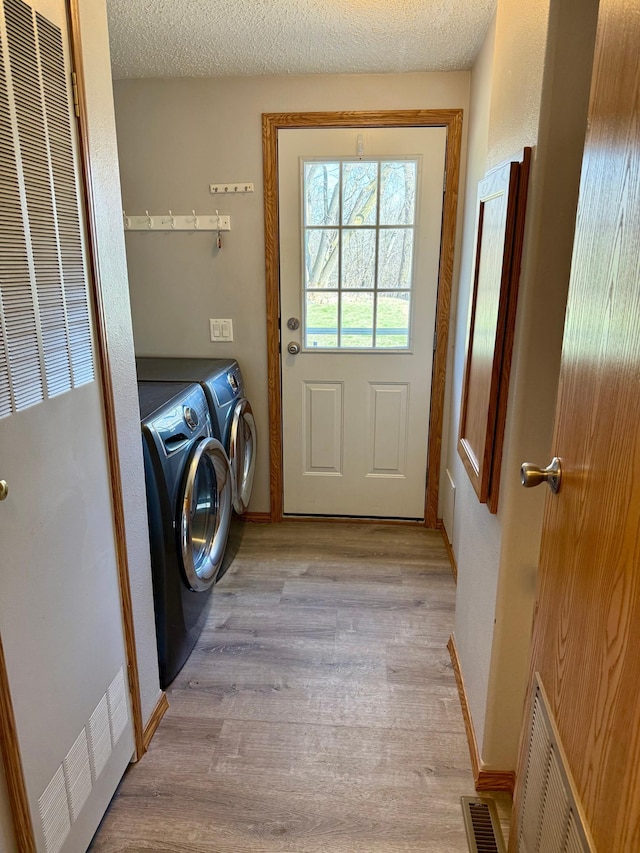 20361 Rolling Acres Dr, Eden Lake Twp, MN 56368 - clothes washing area with a heating unit, washer and dryer, light wood-style flooring, baseboards, and a textured ceiling