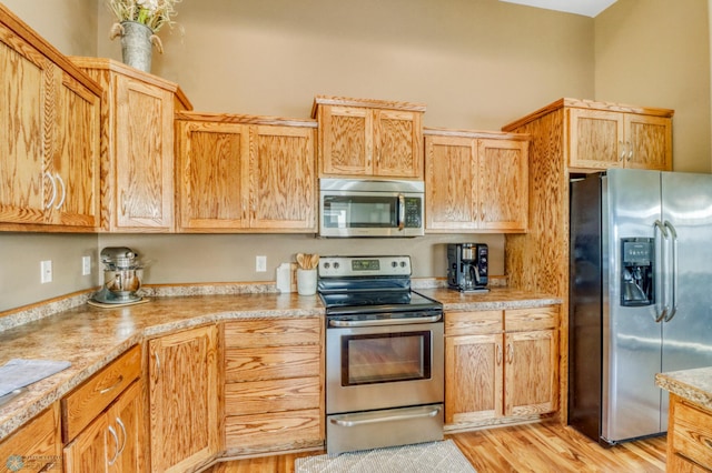 kitchen featuring light countertops, stainless steel appliances, and light wood finished floors
