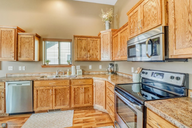 kitchen featuring a sink, appliances with stainless steel finishes, light wood-style floors, and light countertops