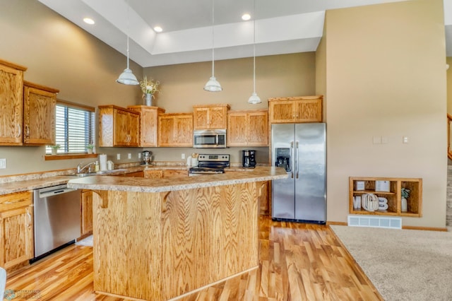 kitchen with visible vents, light wood-style flooring, a towering ceiling, and appliances with stainless steel finishes