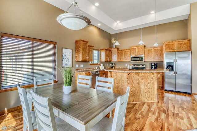 dining room with recessed lighting, light wood-style flooring, and a towering ceiling