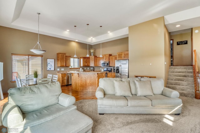 living room featuring stairs, recessed lighting, wood finished floors, and a raised ceiling