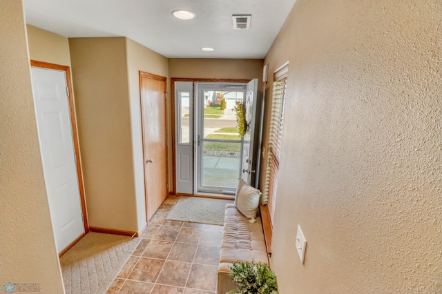 foyer entrance with visible vents, recessed lighting, a textured wall, and baseboards