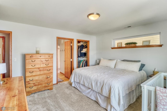carpeted bedroom featuring a walk in closet, a closet, and visible vents