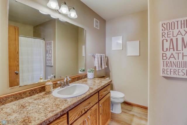 bathroom with vanity, toilet, curtained shower, wood finished floors, and visible vents