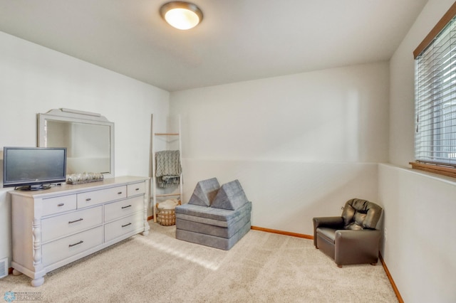 living area featuring baseboards and light colored carpet