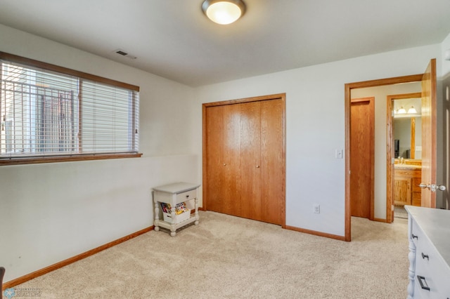 unfurnished bedroom featuring baseboards, light colored carpet, visible vents, and a closet