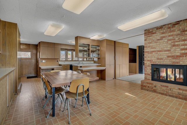 420 6th Ave N, Cold Spring, MN 56320 - dining space with wood walls, a textured ceiling, brick floor, and a brick fireplace
