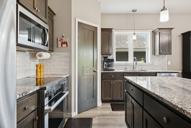 1703 11th St NE, Buffalo, MN 55313 - kitchen with appliances with stainless steel finishes, a sink, decorative backsplash, and light wood-style floors