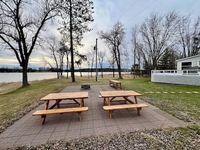 surrounding community with a deck with water view and a yard