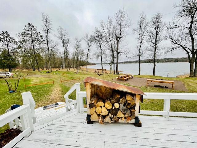 wooden terrace featuring a water view and a lawn