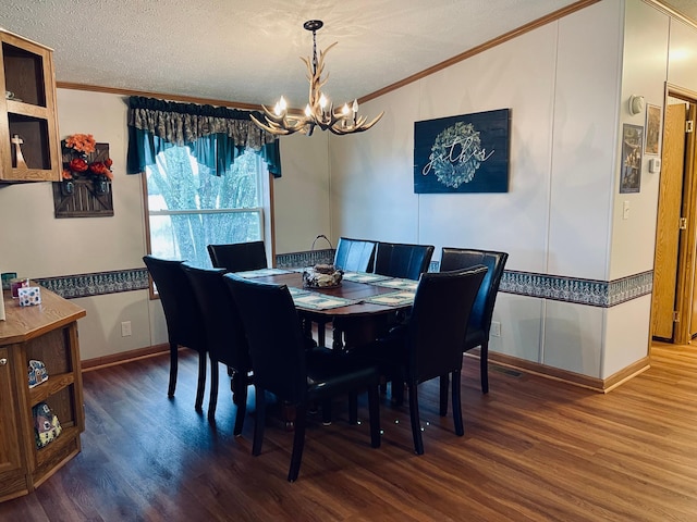 dining room featuring a textured ceiling, wood finished floors, ornamental molding, and a notable chandelier