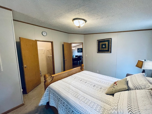 bedroom with a closet, ornamental molding, a textured ceiling, carpet floors, and a spacious closet