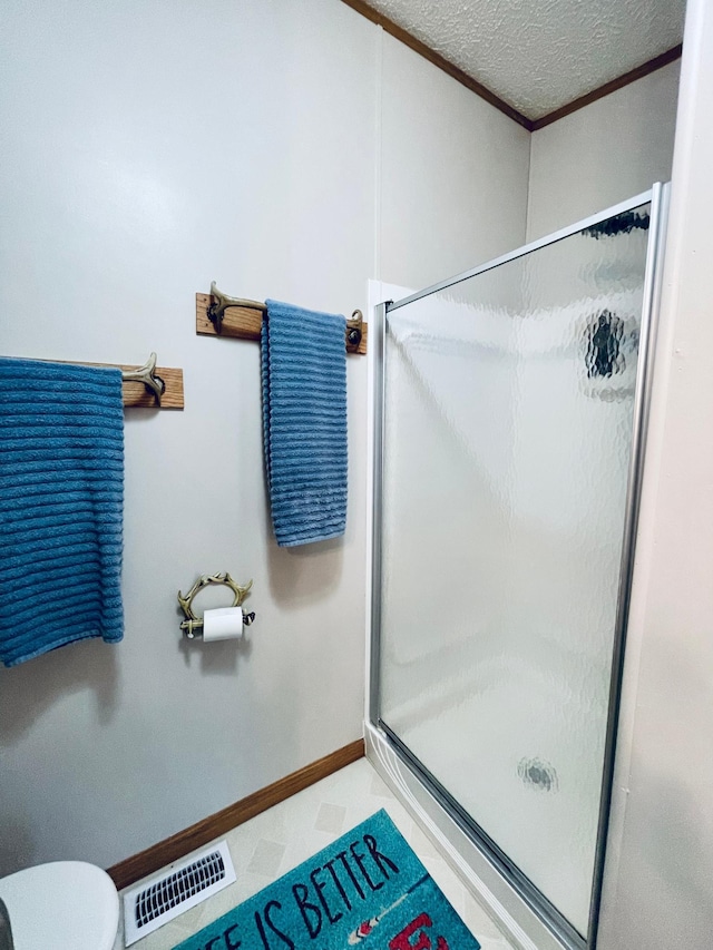 bathroom with a textured ceiling, a shower stall, visible vents, baseboards, and toilet