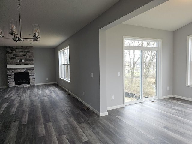 17121 61st St NE, Otsego, MN 55330 - unfurnished living room with baseboards, dark wood finished floors, a chandelier, and a stone fireplace