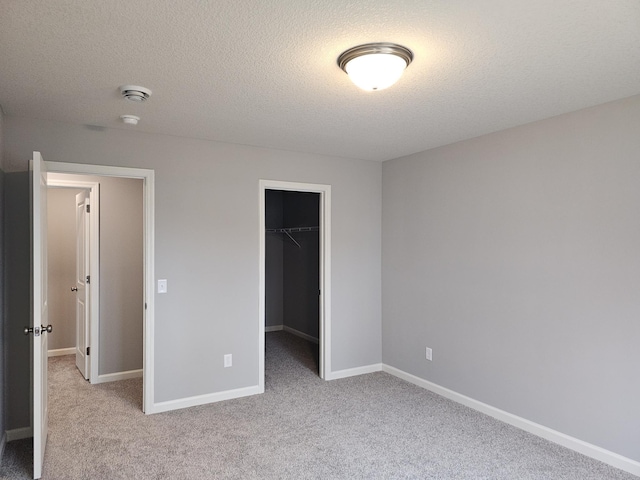 17121 61st St NE, Otsego, MN 55330 - unfurnished bedroom featuring a walk in closet, a textured ceiling, baseboards, a closet, and carpet