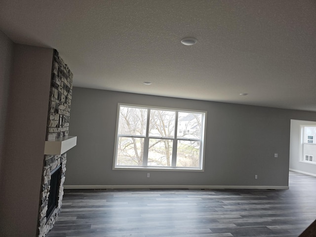 17121 61st St NE, Otsego, MN 55330 - unfurnished living room featuring baseboards, a fireplace, dark wood-style flooring, and a textured ceiling