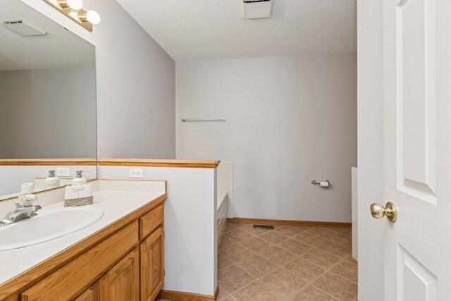 3662 Pond View Pt, Eagan, MN 55122 - bathroom featuring a textured ceiling, vanity, a bathtub, tile patterned flooring, and baseboards