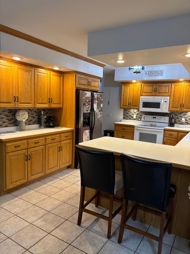 kitchen with light tile patterned floors, brown cabinets, white appliances, and tasteful backsplash