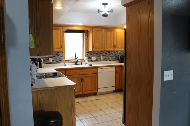 kitchen featuring decorative backsplash, white dishwasher, light countertops, light tile patterned floors, and a sink