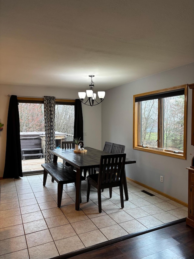 dining space with baseboards, plenty of natural light, visible vents, and a chandelier