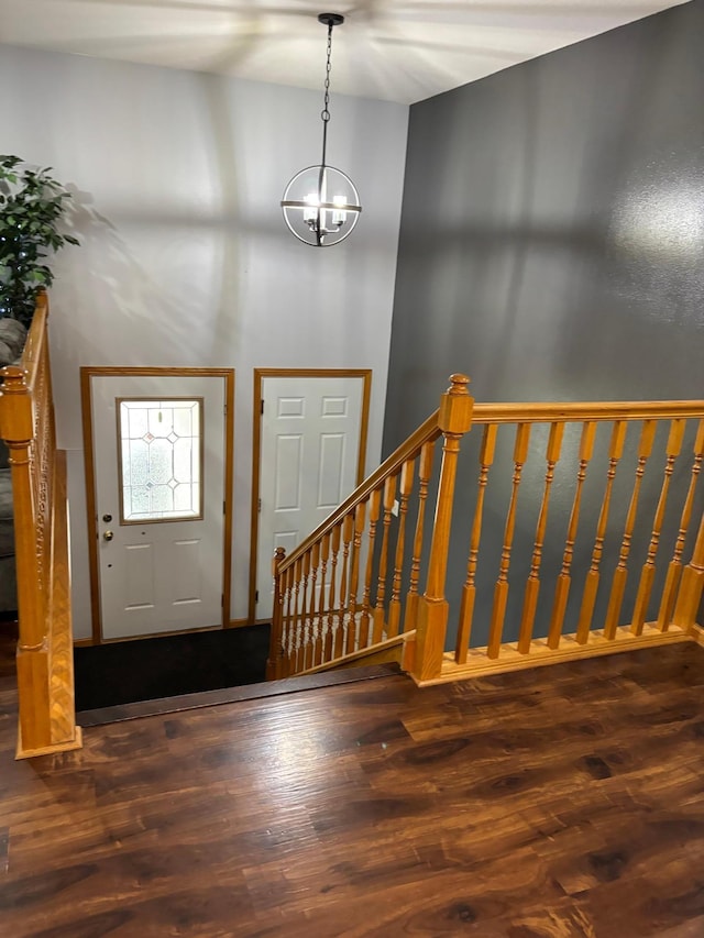 foyer with a high ceiling, wood finished floors, a notable chandelier, and stairway