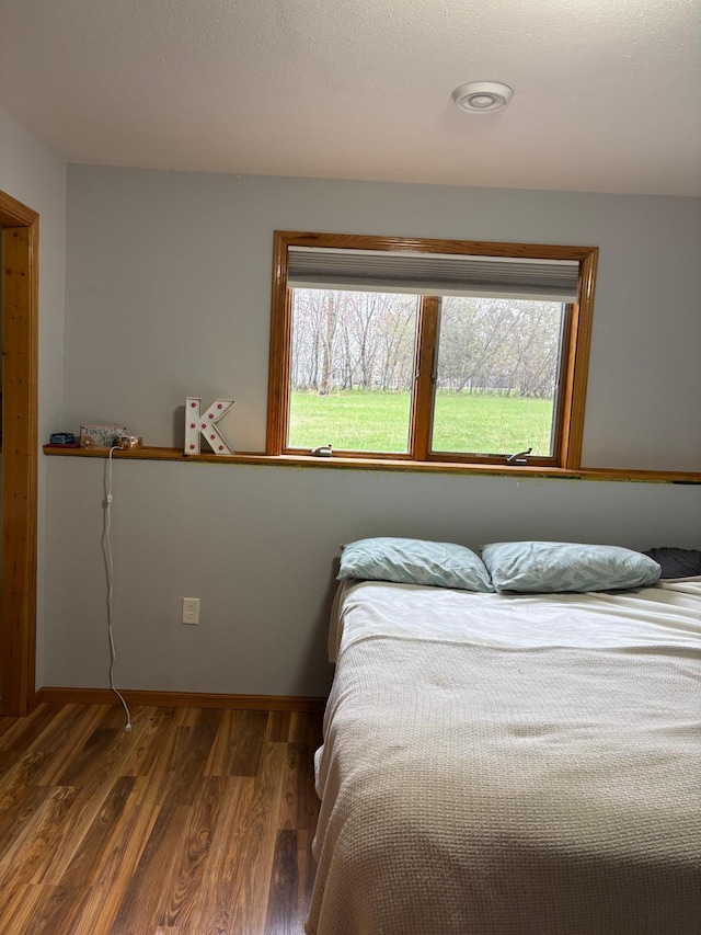 bedroom with baseboards, multiple windows, and wood finished floors