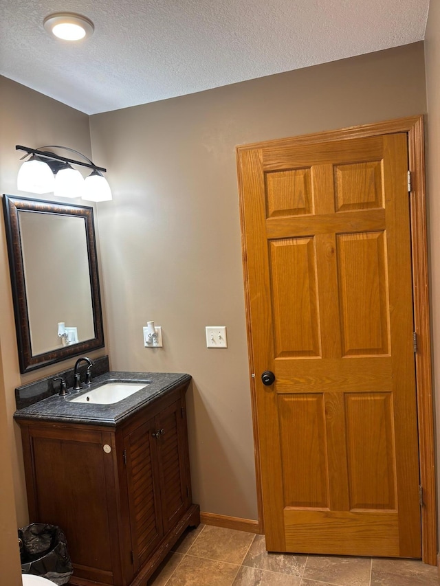 bathroom with vanity, a textured ceiling, and baseboards