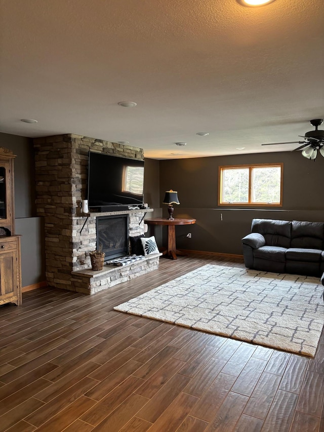 living area with baseboards, a ceiling fan, wood finished floors, and a fireplace