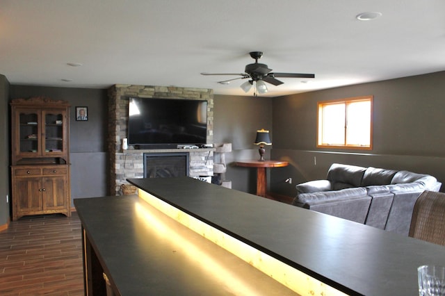 living room with a ceiling fan, a fireplace, baseboards, recessed lighting, and dark wood-type flooring