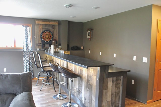 bar with a dry bar and light wood-type flooring