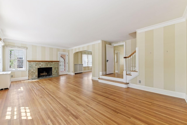 4606 Drexel Ave, Edina, MN 55424 - unfurnished living room featuring wallpapered walls, plenty of natural light, light wood-style flooring, ornamental molding, and arched walkways