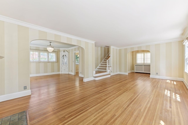 4606 Drexel Ave, Edina, MN 55424 - unfurnished living room with arched walkways, radiator, wallpapered walls, ornamental molding, and light wood finished floors