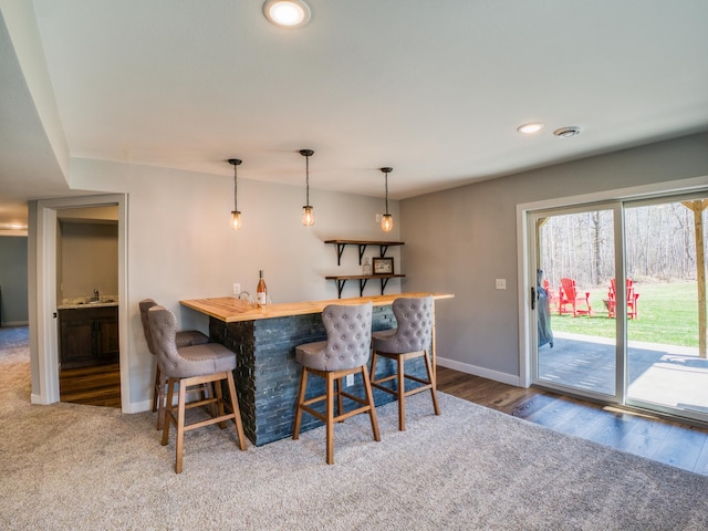 dining area featuring a dry bar, baseboards, recessed lighting, wood finished floors, and carpet floors