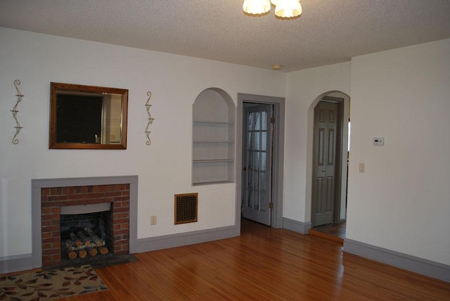 767 Shoreacres Dr, Fairmont, MN 56031 - unfurnished living room with a fireplace, arched walkways, visible vents, a textured ceiling, and wood finished floors