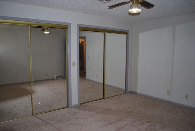 767 Shoreacres Dr, Fairmont, MN 56031 - unfurnished bedroom with two closets, carpet, visible vents, a ceiling fan, and a textured ceiling