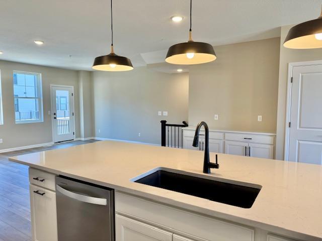 kitchen with pendant lighting, open floor plan, dishwasher, and a sink