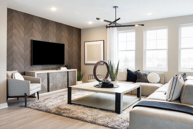 living room featuring recessed lighting, a notable chandelier, baseboards, an accent wall, and wood finished floors