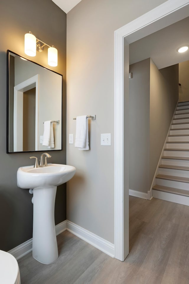 bathroom featuring baseboards, wood finished floors, and toilet