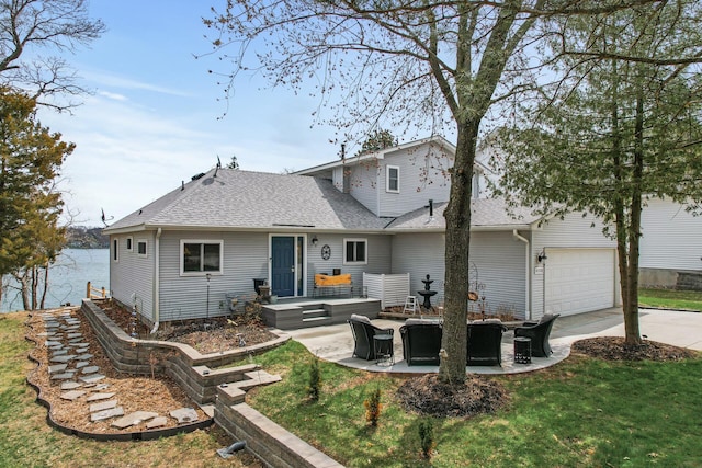 back of property featuring a garage, roof with shingles, a yard, and driveway