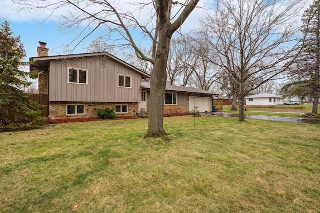back of house with board and batten siding, a chimney, a garage, aphalt driveway, and a yard