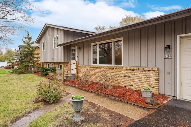 view of front of home with brick siding, board and batten siding, and a front yard